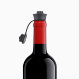 Red wine bottle with a black screw cap and attached plastic tether.