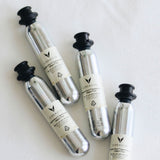 Four silver CO2 canisters labeled "Coravin Pure Sparkling CO2" lying on a white surface.