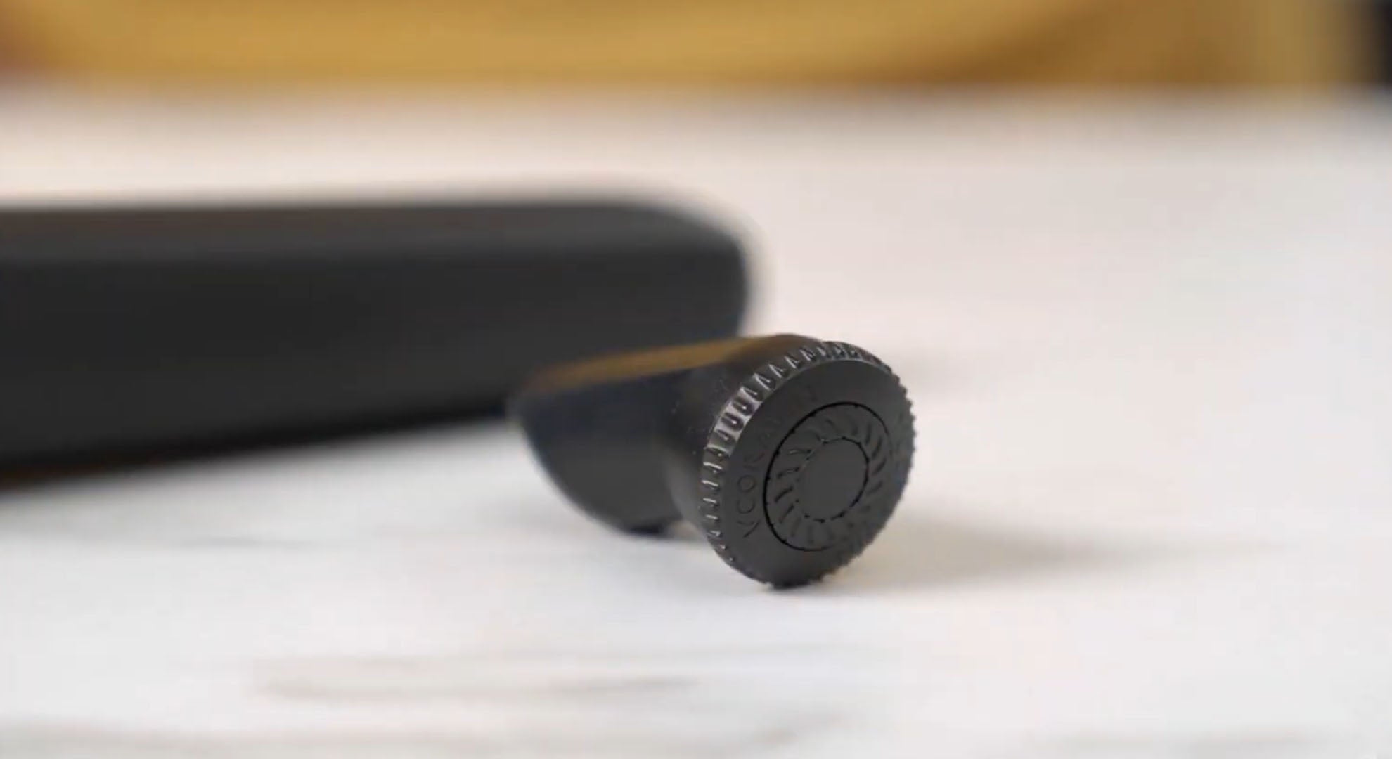 Black rubber stopper rests on a light surface, with a smooth cylindrical shape and a textured edge for grip.