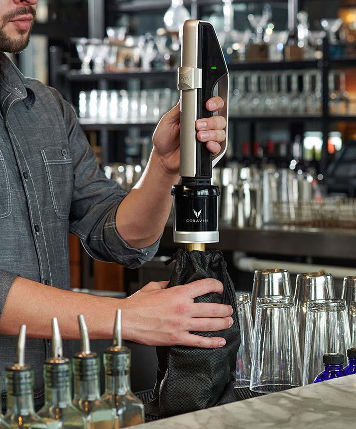 A bartender uses a Coravin wine preservation system to pour wine from a bottle without removing the cork.