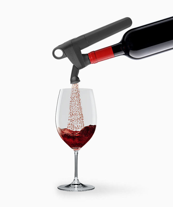A red wine bottle pouring into a glass with bubbles rising, showcasing an aerator attachment.